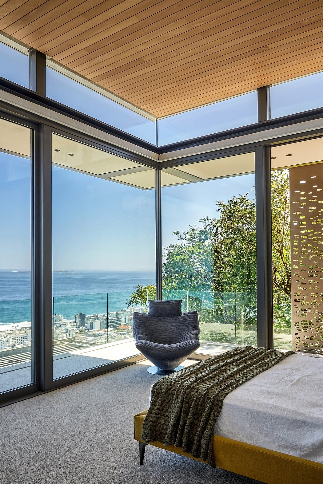 Stunning floor-to-ceiling glass walls showcase panoramic ocean views in this modern bedroom.
