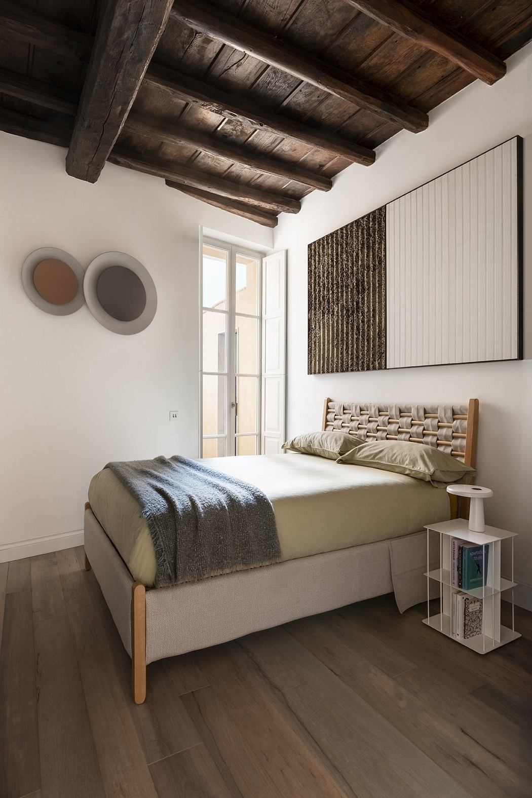 Rustic bedroom with exposed wooden beams, modern furnishings, and textural elements.