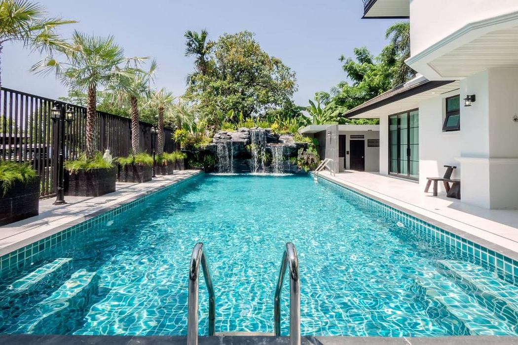 A luxurious tropical villa with a stunning pool, lush vegetation, and modern architectural design.