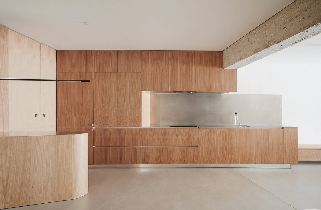 Minimalist kitchen with sleek wood cabinetry, stainless steel appliances, and concrete floors.