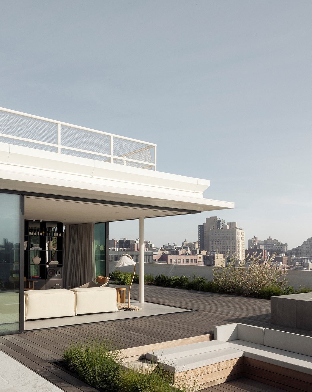 Modern rooftop terrace with sleek furniture, glass walls, and a stunning cityscape view.