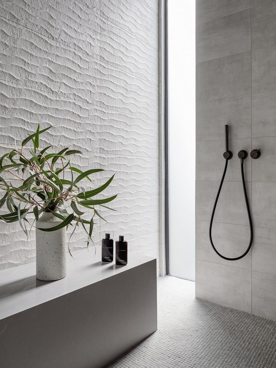 Minimalist bathroom features textured gray walls, sleek black fixtures, and a potted plant.
