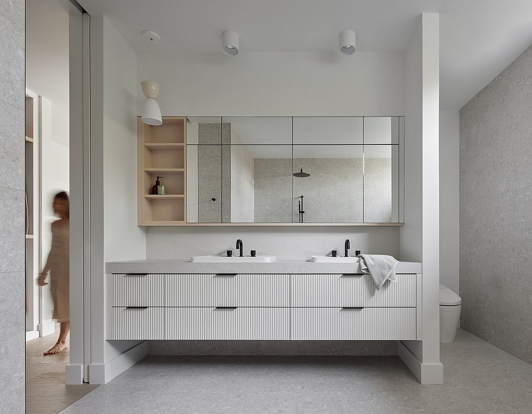 Minimalist bathroom interior with sleek cabinetry, large mirror, and neutral color palette.