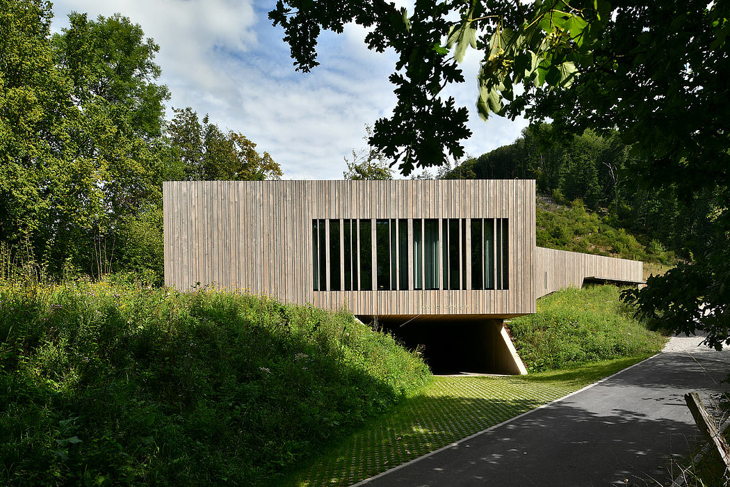 A modern, rectangular wooden structure bridge spanning a lush, forested landscape.