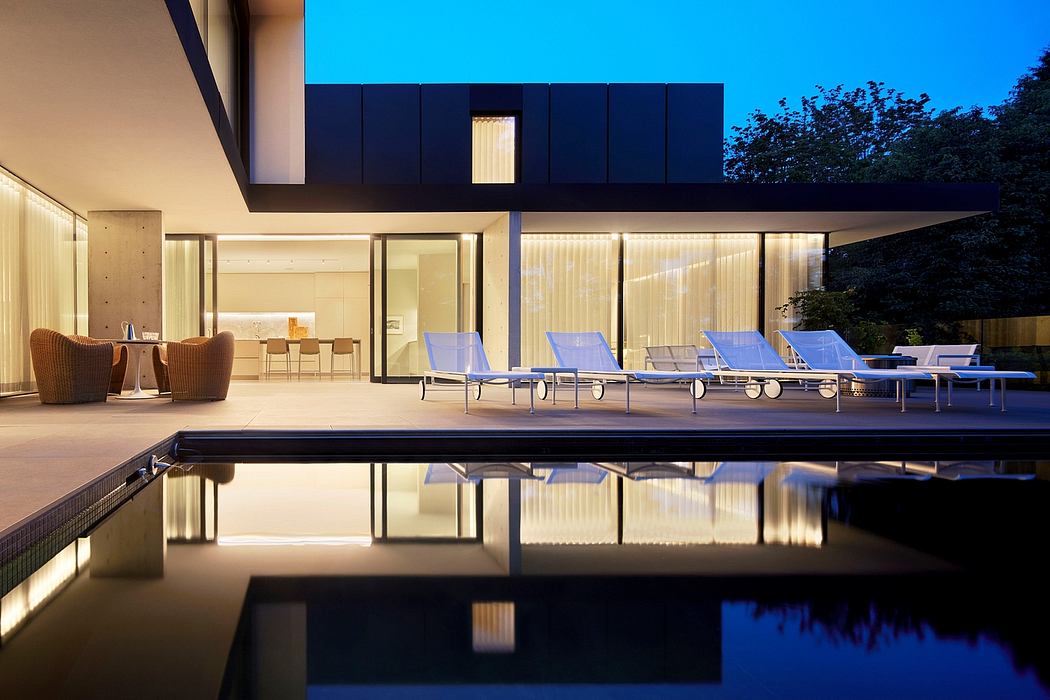 Modern minimalist architecture with a pool, lounge chairs, and glass walls reflecting the sky.