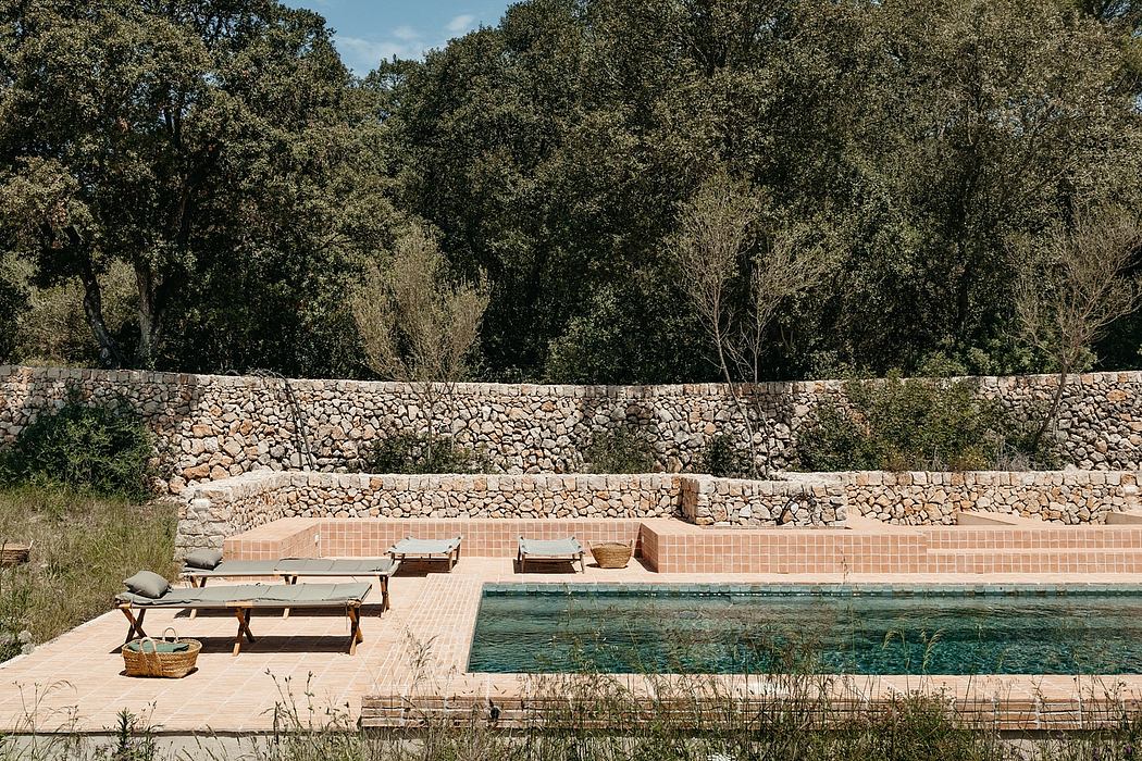 Rustic stone wall surrounding a tiled pool area with wooden benches and planters.