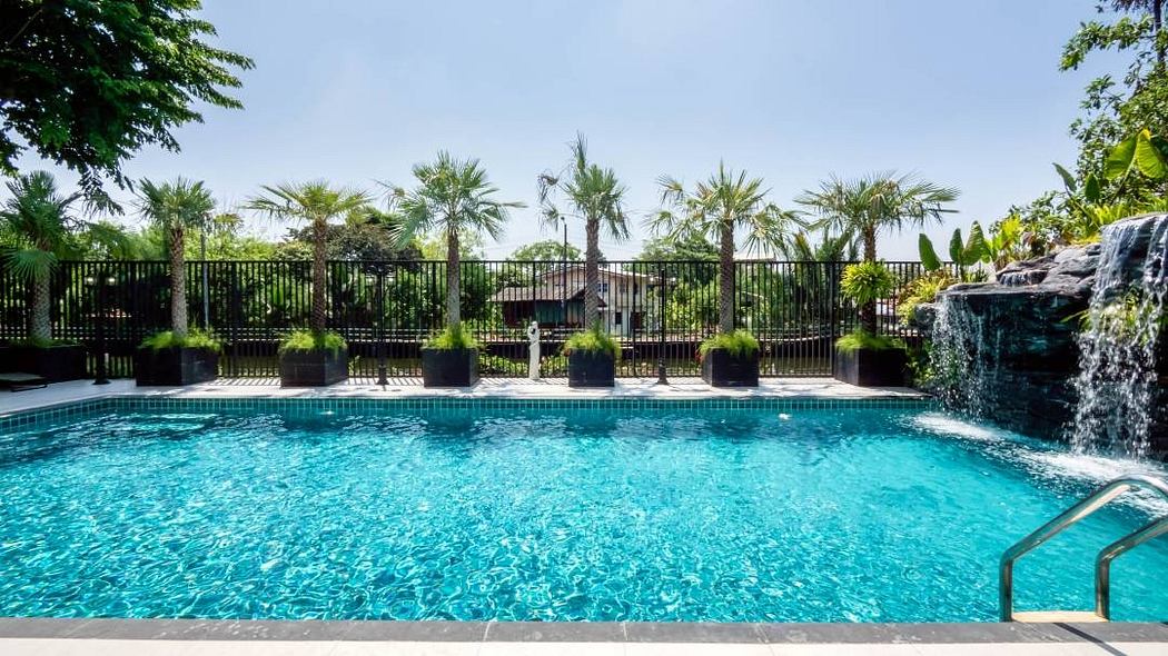 Inviting tropical oasis with crystal-clear pool, palm trees, and tiled waterfall.