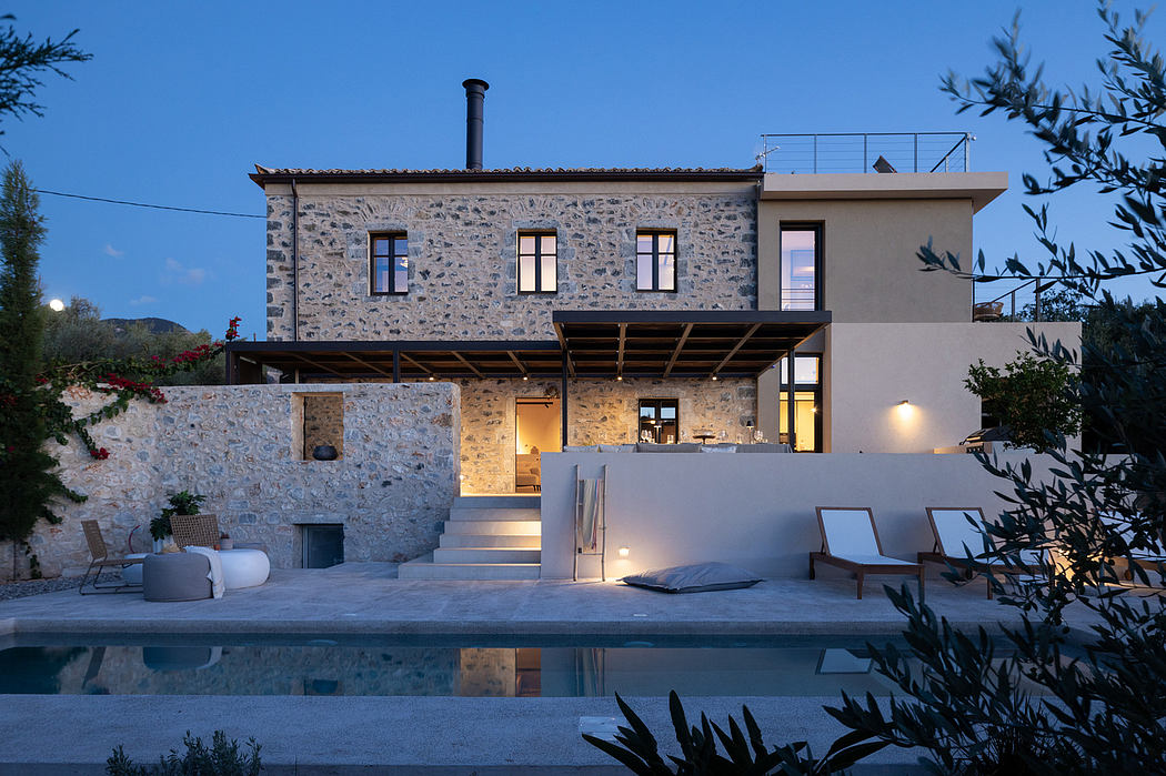 A modern stone villa with a wooden roof terrace, pool, and lush landscaping.