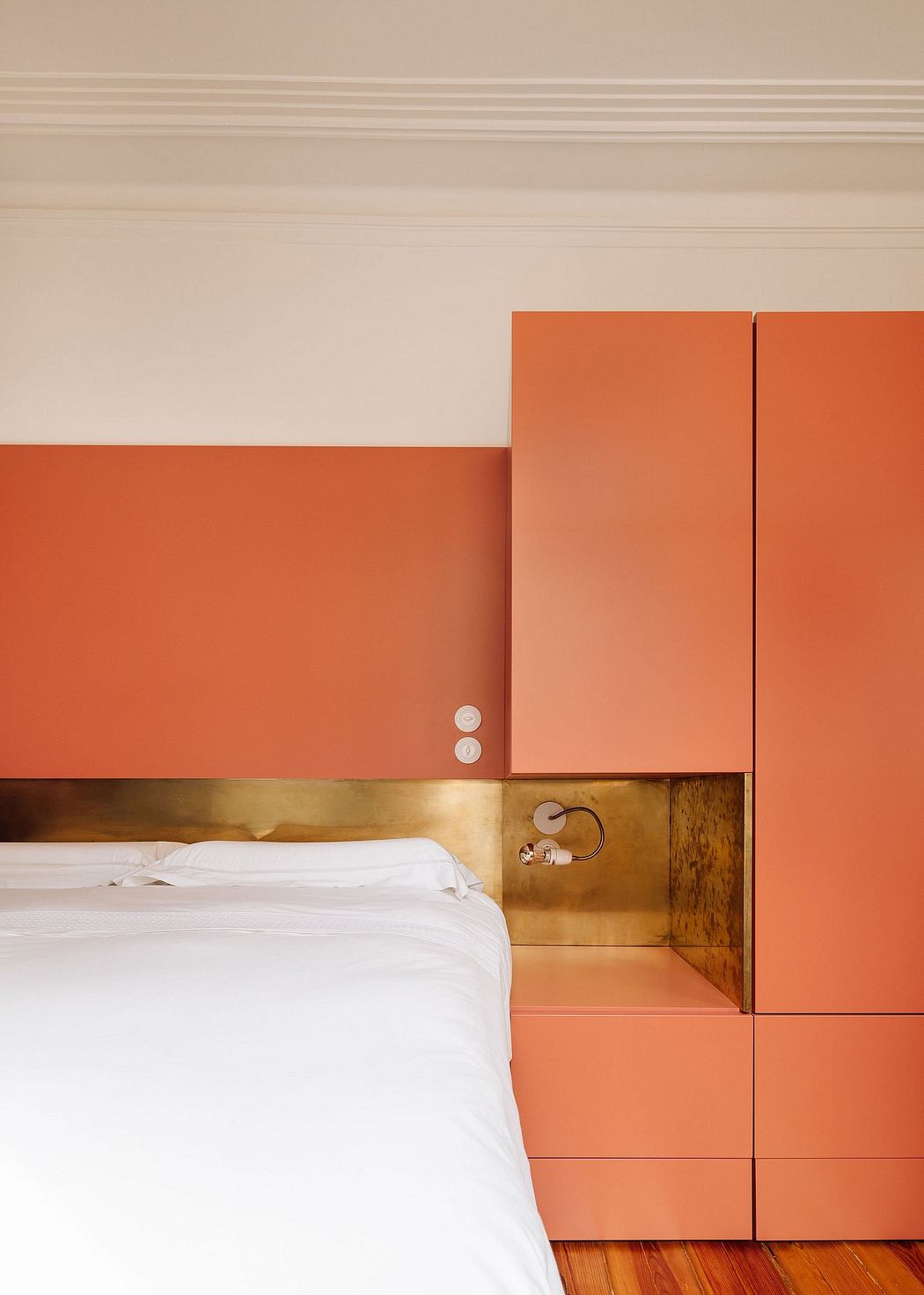 A modern bedroom with vibrant orange walls, sleek built-in cabinets, and warm wood accents.