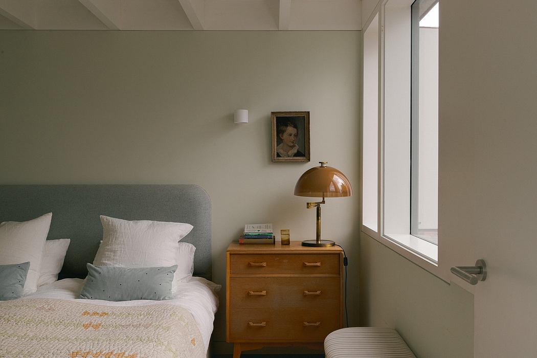 Cozy bedroom with muted tones, wood furniture, and an elegant portrait on the wall.