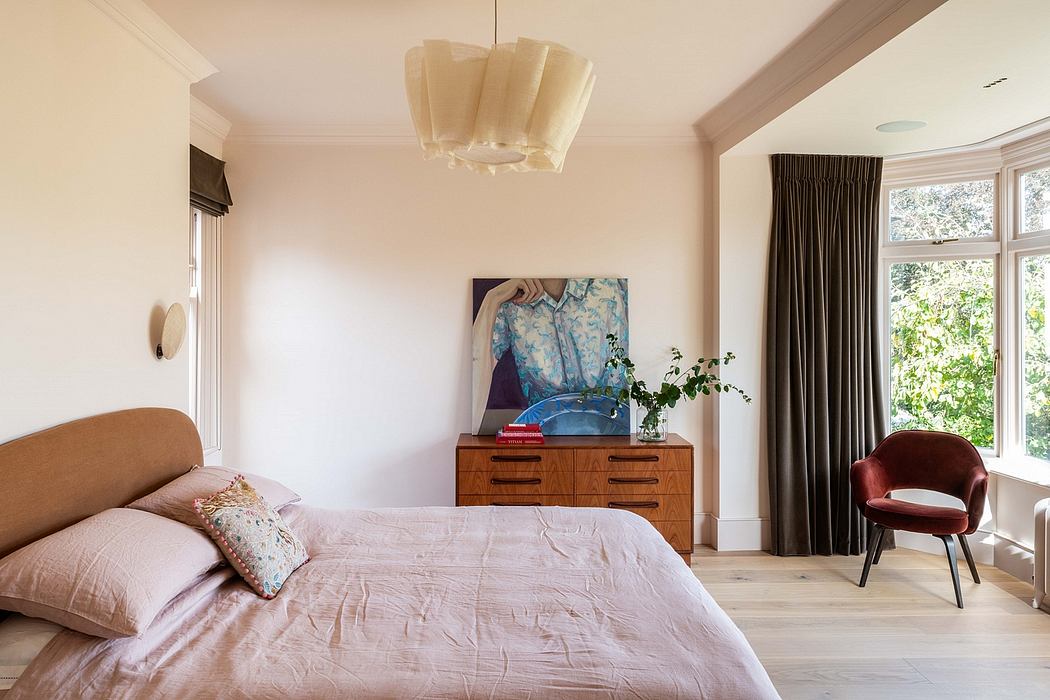 A cozy bedroom with a mid-century dresser, modern chandelier, and vibrant artwork.