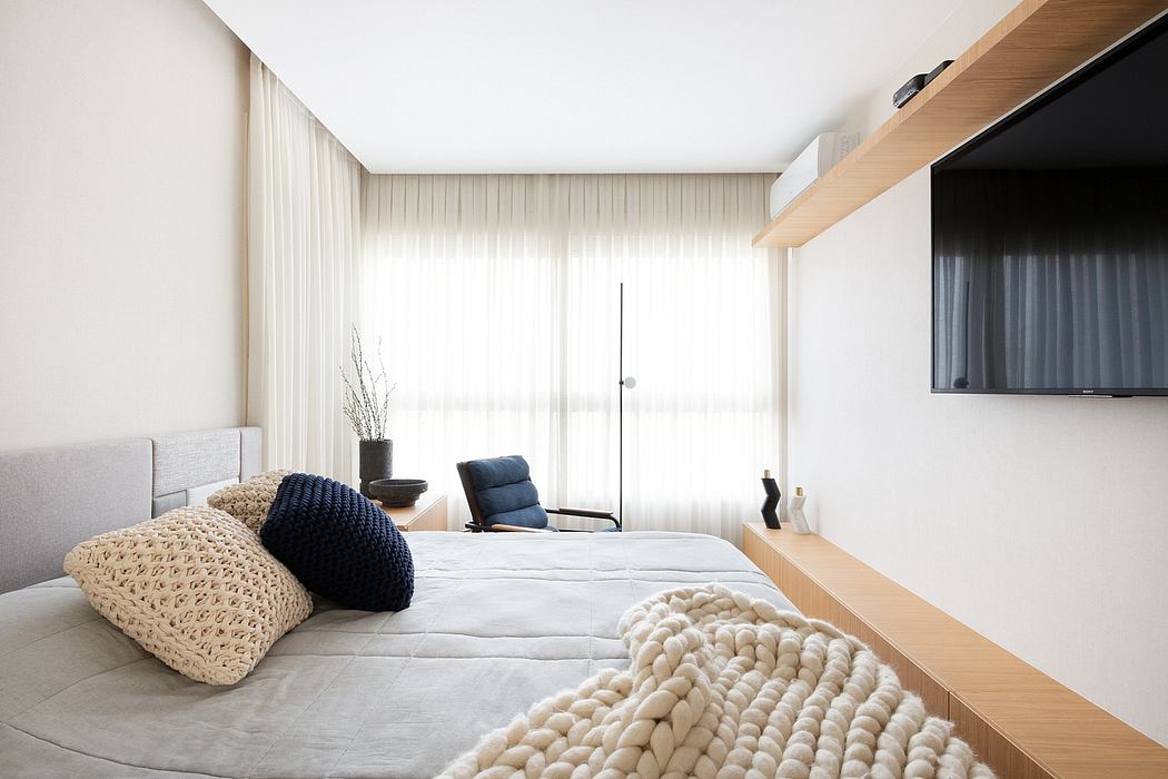 Minimalist bedroom with plush textiles, built-in shelving, and a large window providing natural light.