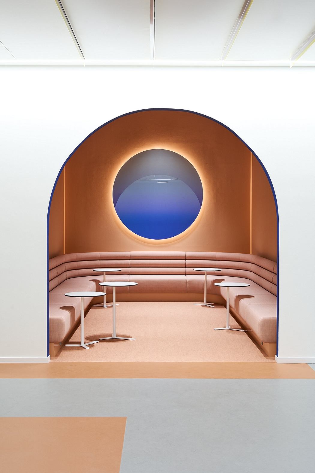 Modern, sunken seating area with curved, illuminated alcove and circular blue niche.
