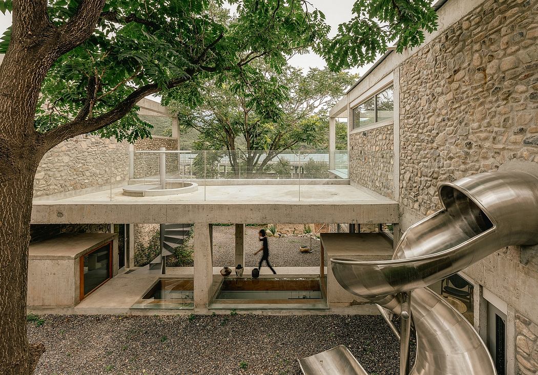Modernist concrete structure with glass walls surrounded by lush greenery.