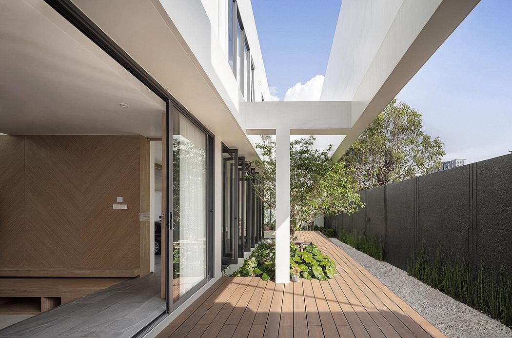 Sleek modern architecture with expansive glass walls, wooden deck, and lush greenery.