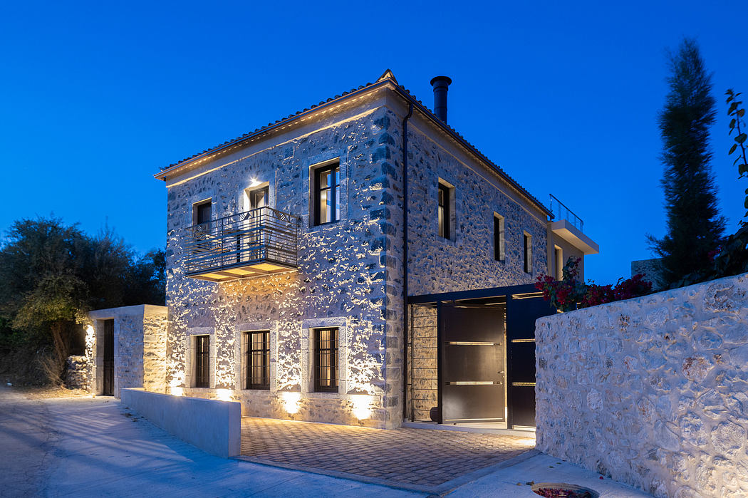 Elegant stone villa with ornate balcony and warm exterior lighting at night.