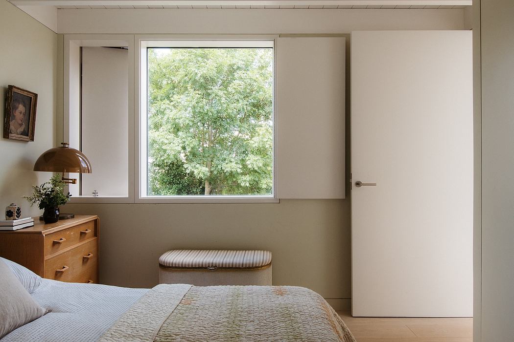 A cozy bedroom with a large window overlooking lush greenery, complemented by warm wood tones.