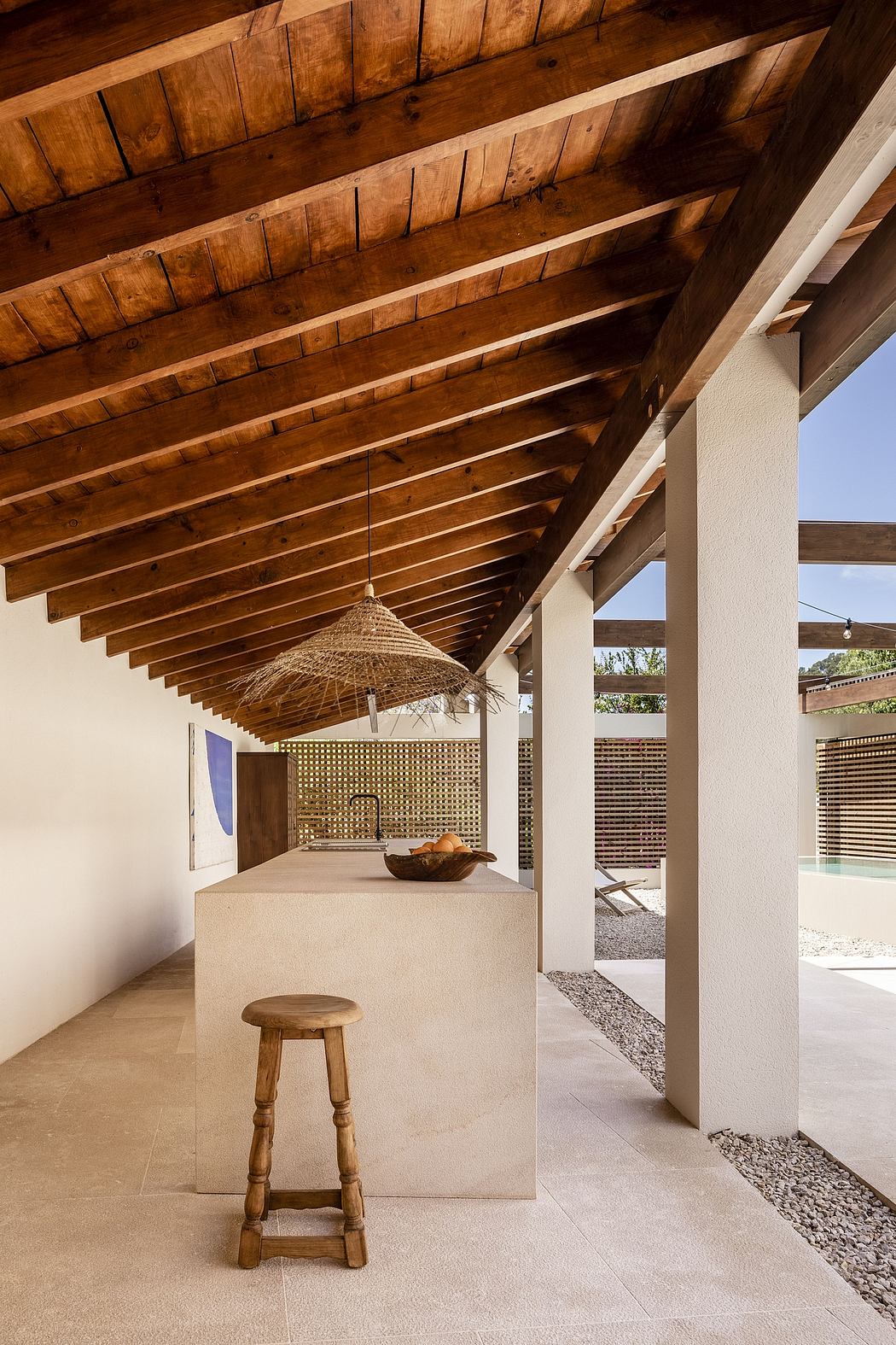 Rustic wooden beams frame an open-air patio with a woven pendant light and minimalist decor.