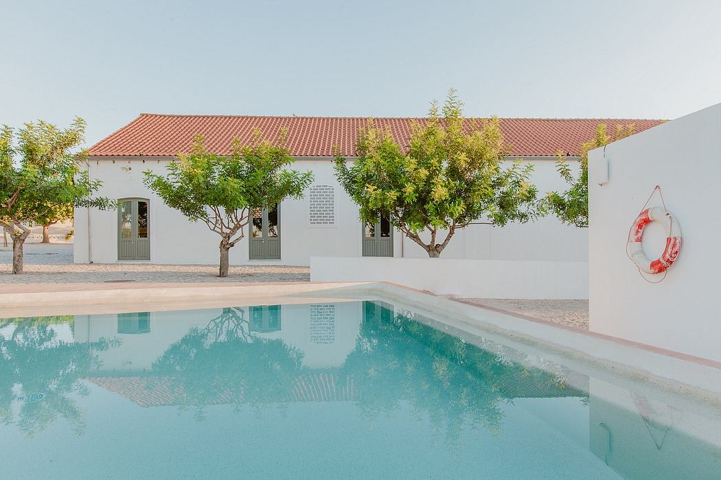 A stylish villa with a red-tiled roof, surrounded by trees and featuring a serene swimming pool.