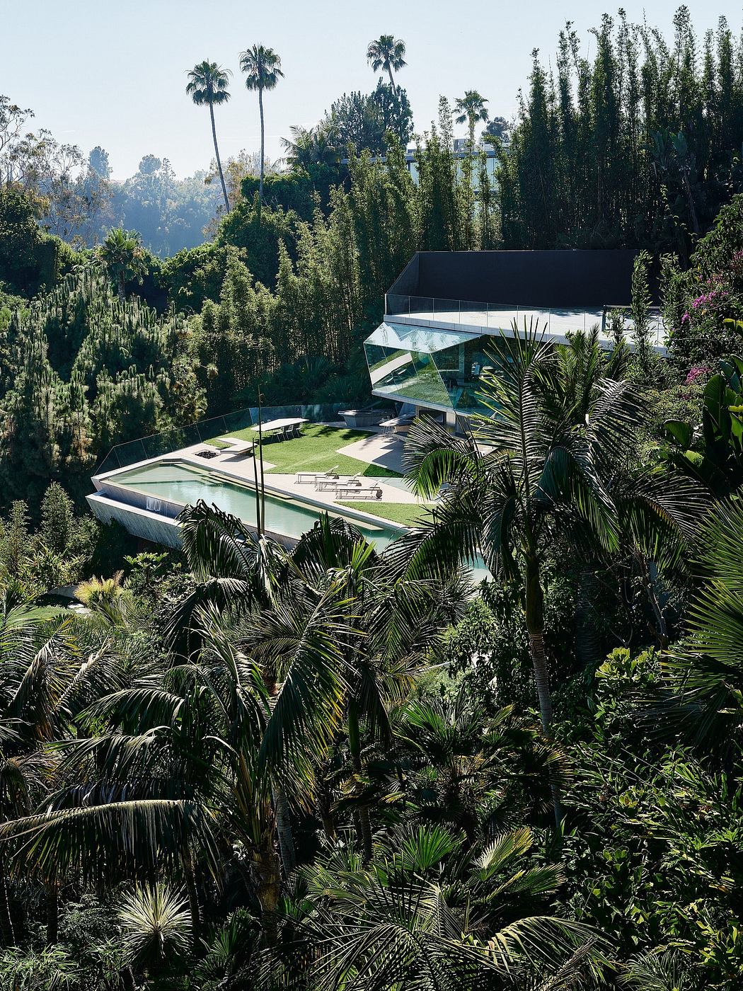 A modern glass and concrete structure nestled in a lush, tropical garden setting.