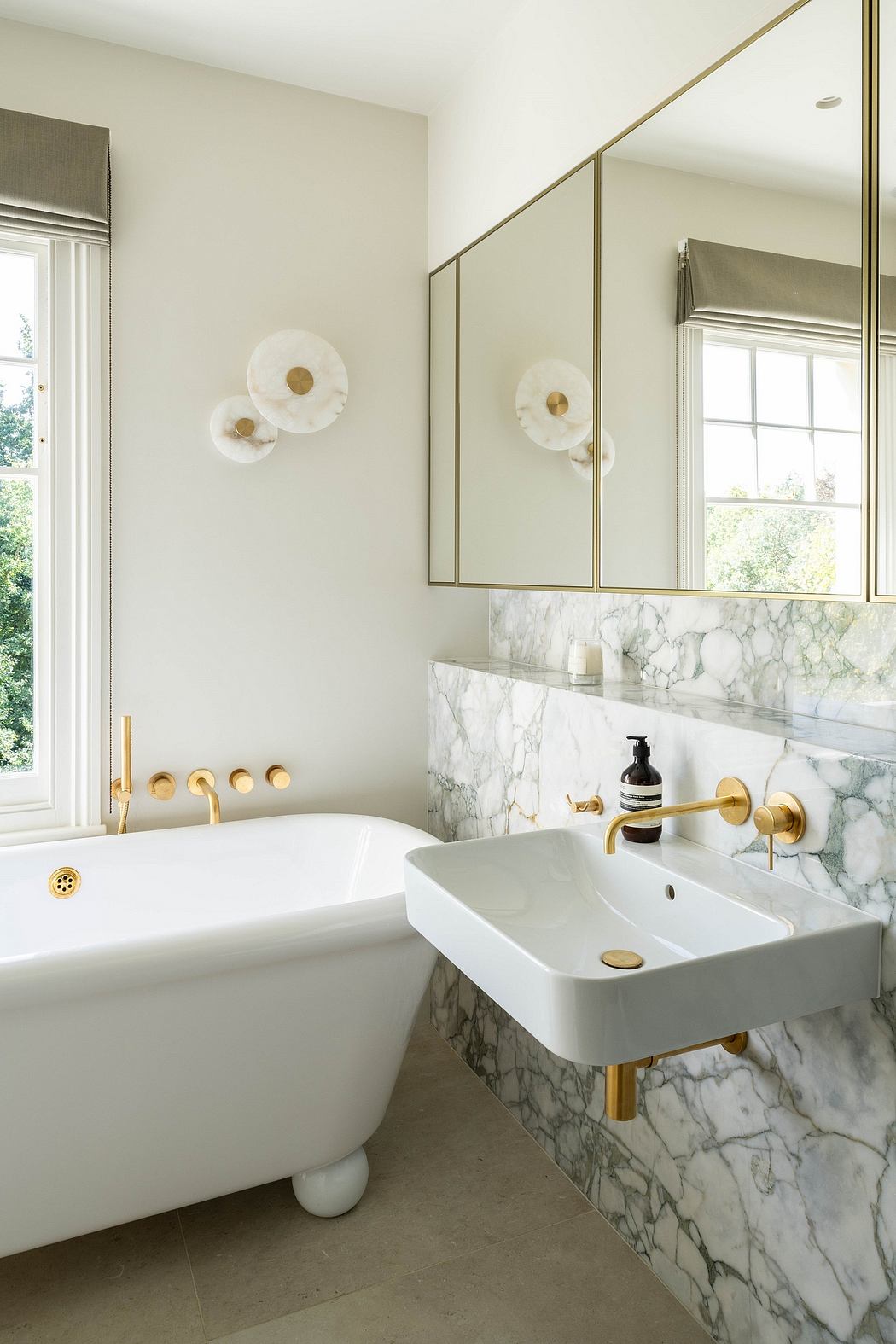 Luxurious bathroom with marble vanity, brass fixtures, and a clawfoot tub.