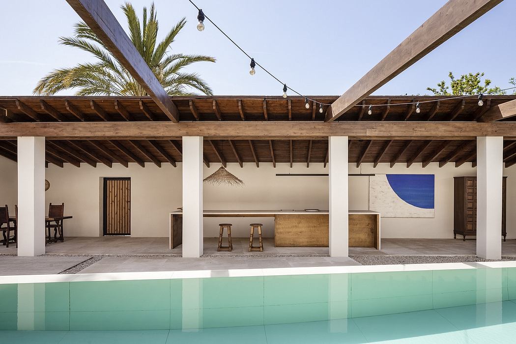 A modern open-air patio with wooden beams, palm trees, and a turquoise pool.