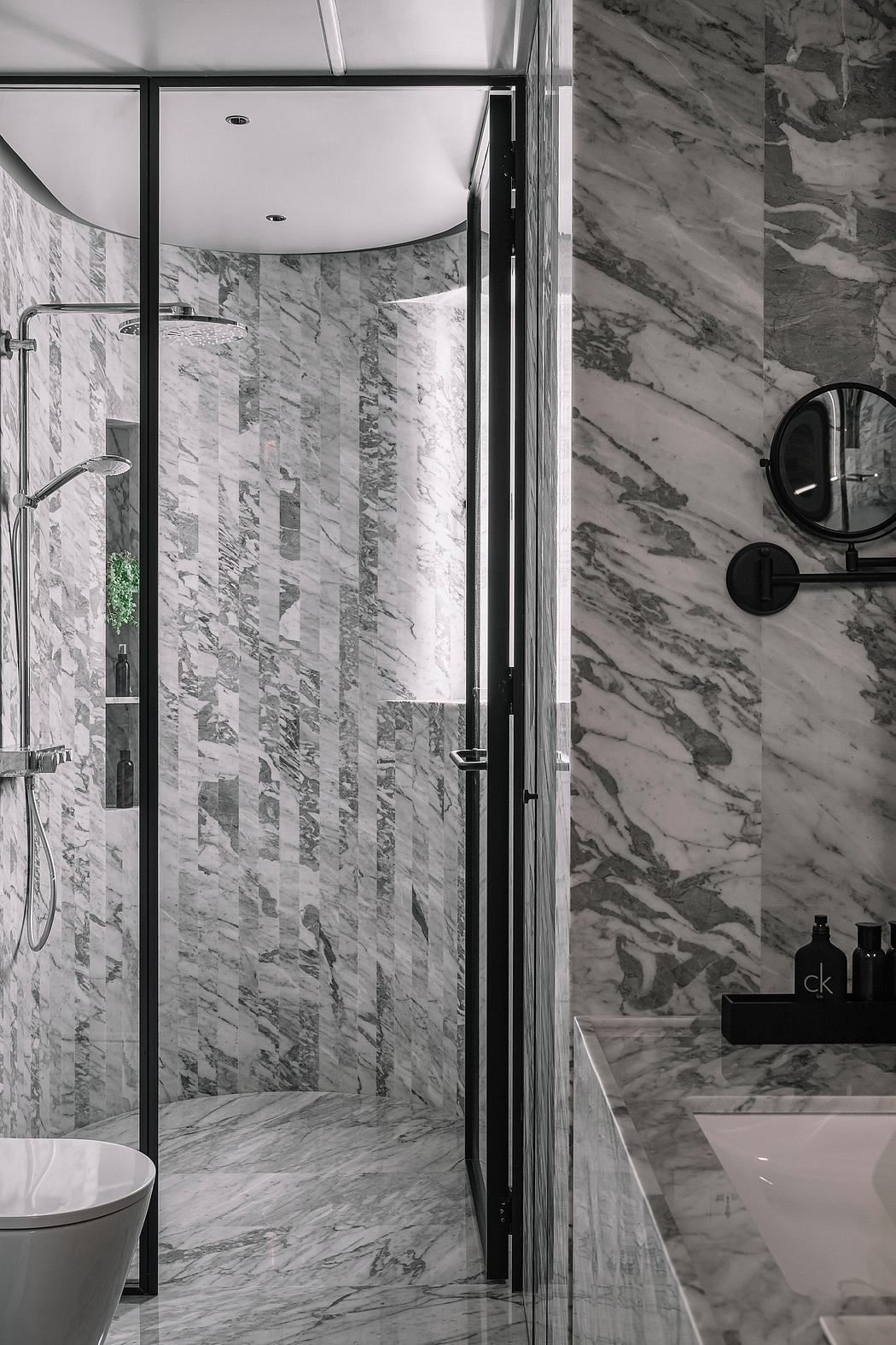Sleek, modern bathroom design featuring marble tile walls, glass shower enclosure, and minimalist fixtures.