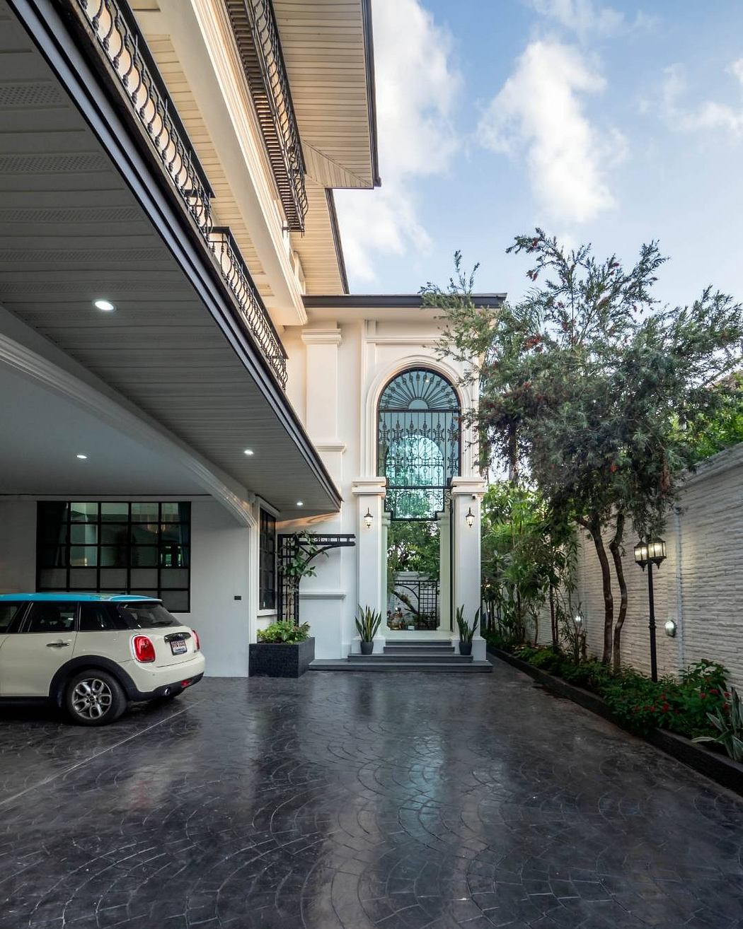 Striking white facade with arched entrances, ornate details, and lush landscaping.