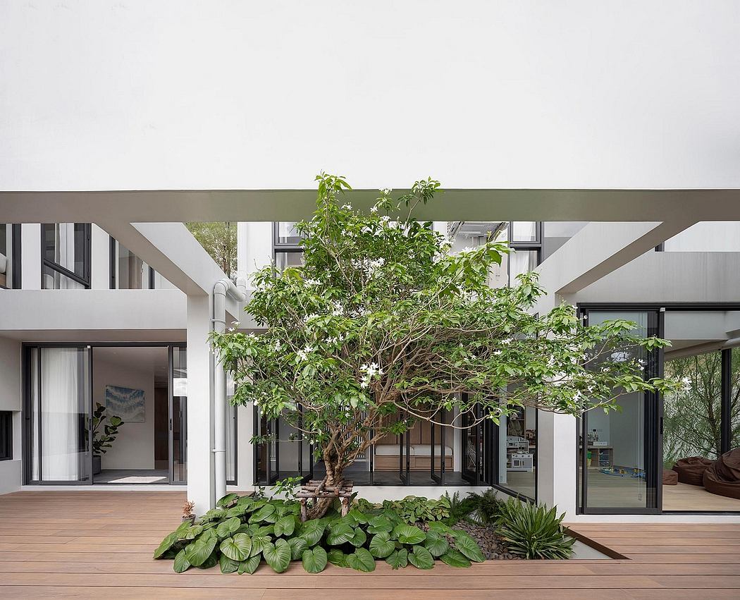 A modern open-concept interior design with a centrally-placed mature tree and surrounding greenery.