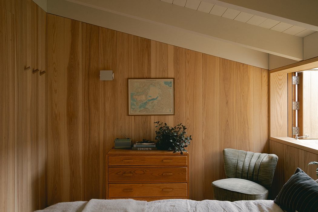 Cozy wood-paneled room with vintage dresser, framed map, and comfy armchair.