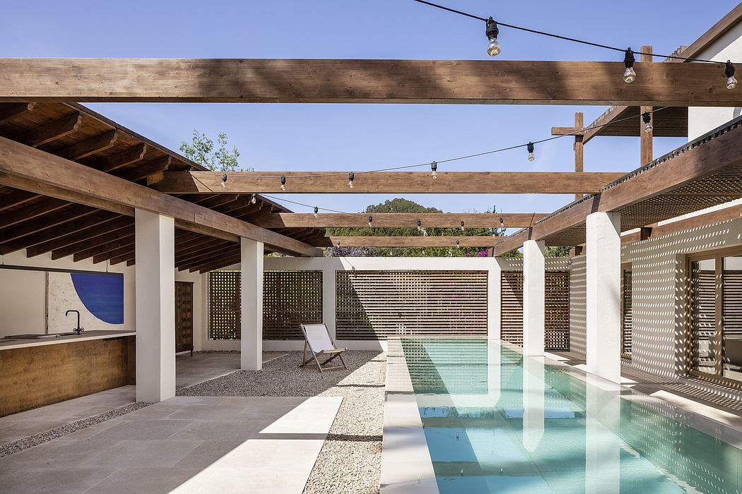 Wooden pergola with string lights, open-air pool area, and minimalist design elements.