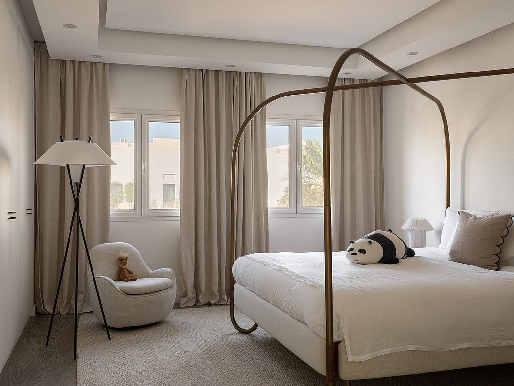 A cozy bedroom with a modern four-poster bed, plush chair, and minimalist decor.