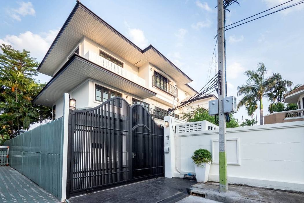 A two-story house with a distinctive roof design, surrounded by a decorative black gate.