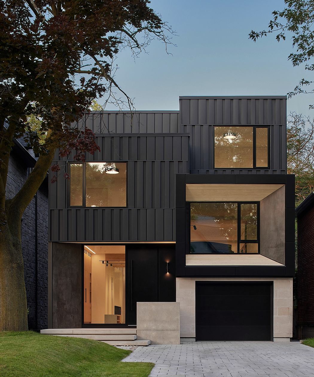 Striking modern home with bold black cladding, angled windows, and sleek garage door.