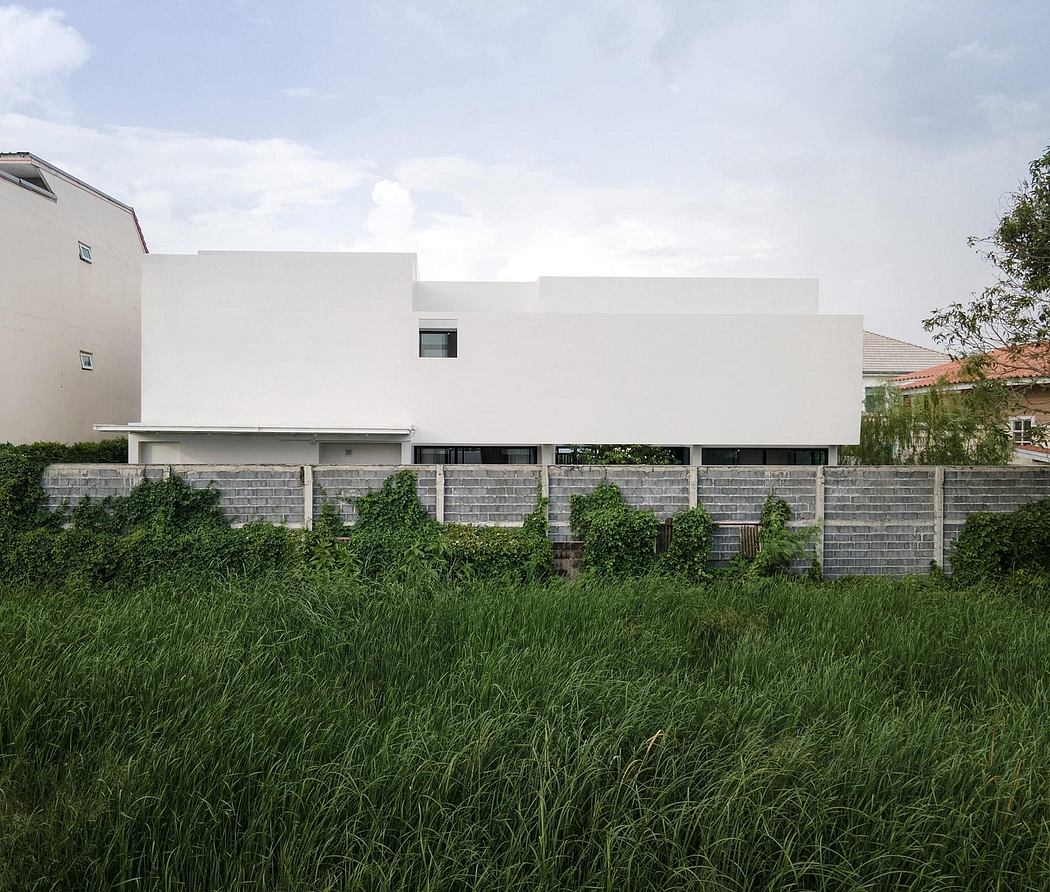 A modern, minimalist building with clean white walls and a stepped concrete facade surrounded by lush greenery.
