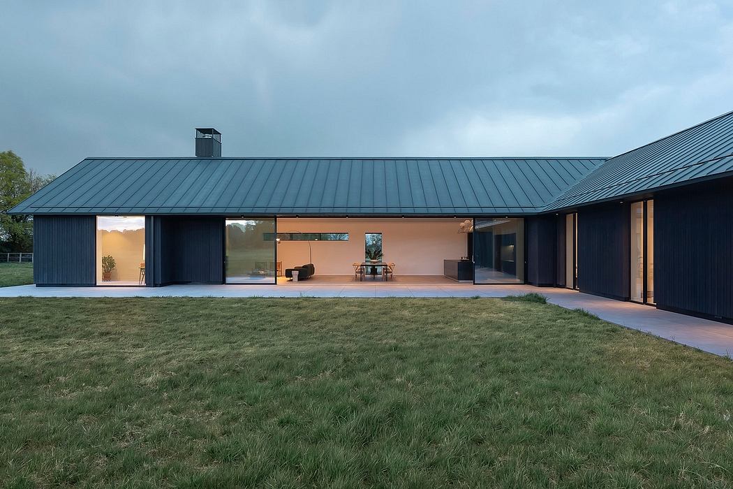Modern single-story house with black metal roof, large windows, and an open-concept interior.
