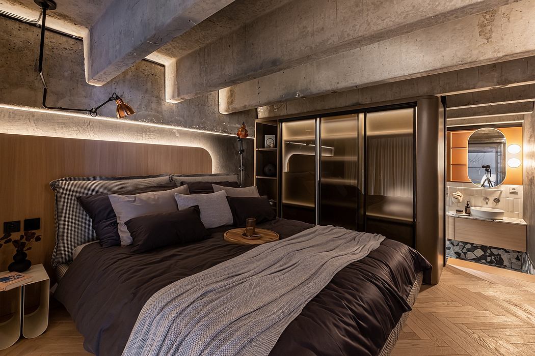 Rustic concrete ceiling beams, sleek black furniture, and warm lighting create a cozy, modern bedroom.