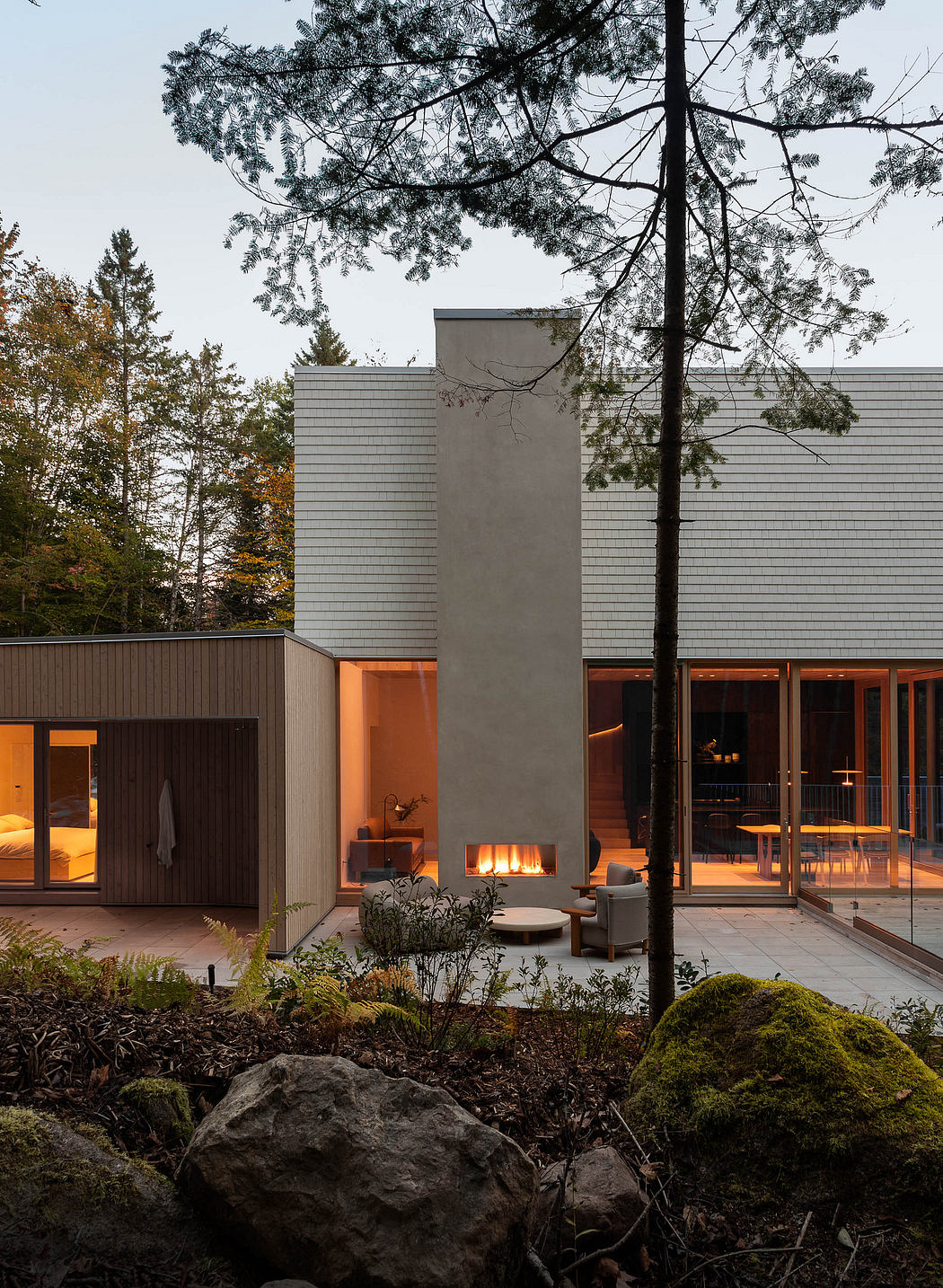 Sleek, modern residence with floor-to-ceiling windows, fireplace, and lush natural surroundings.