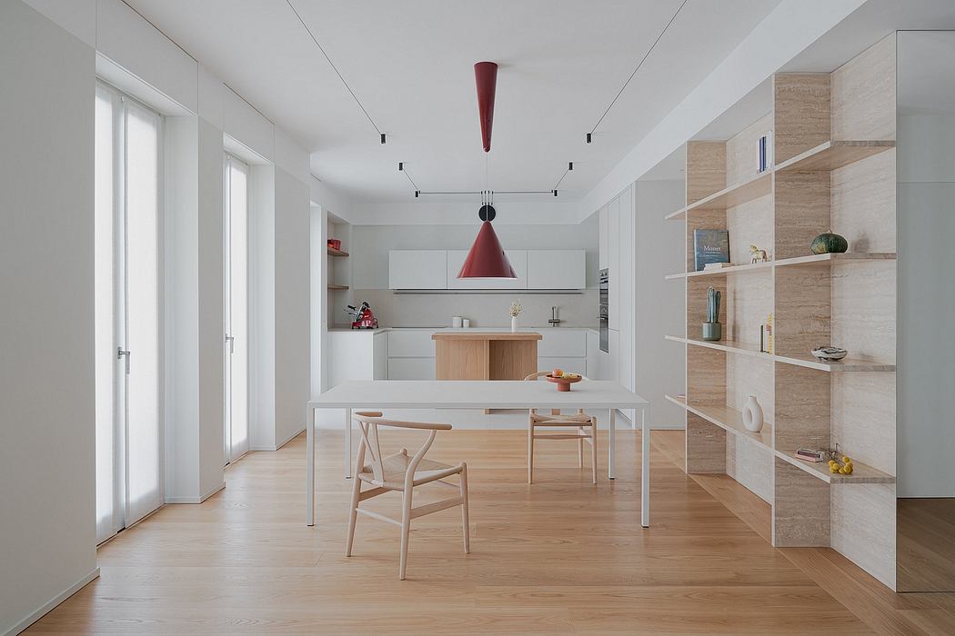 Minimalist kitchen-dining area with a red pendant light and wooden furniture.