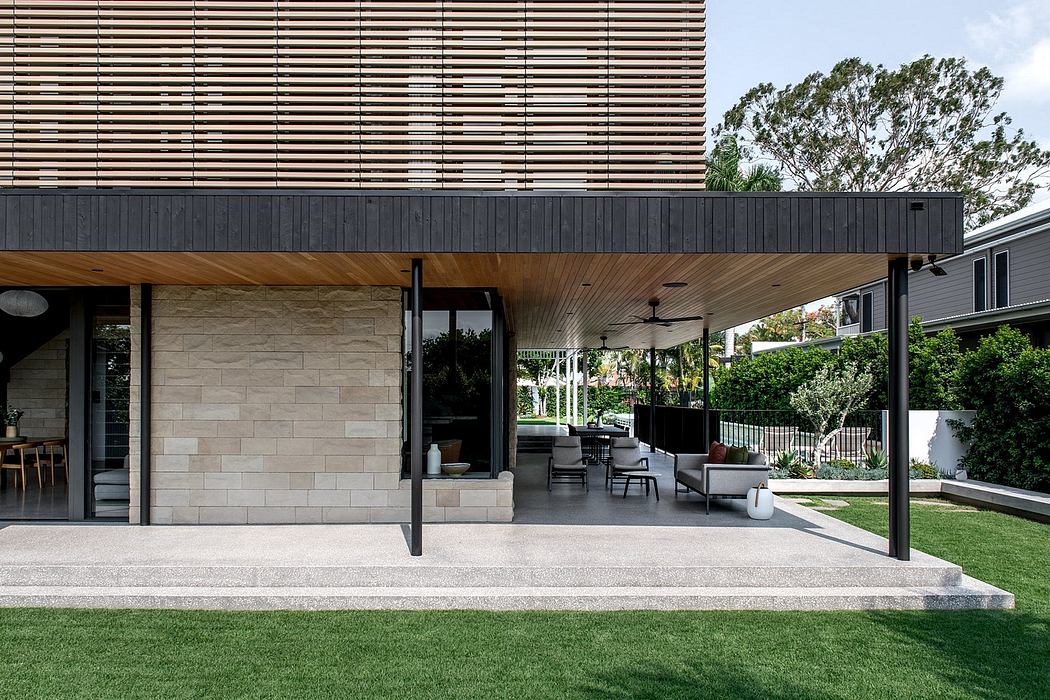 Sleek, modern outdoor patio with wooden canopy, stone walls, and plush seating.
