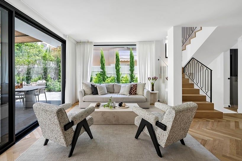 Spacious living area with sleek furniture, large windows, and a lush outdoor view.