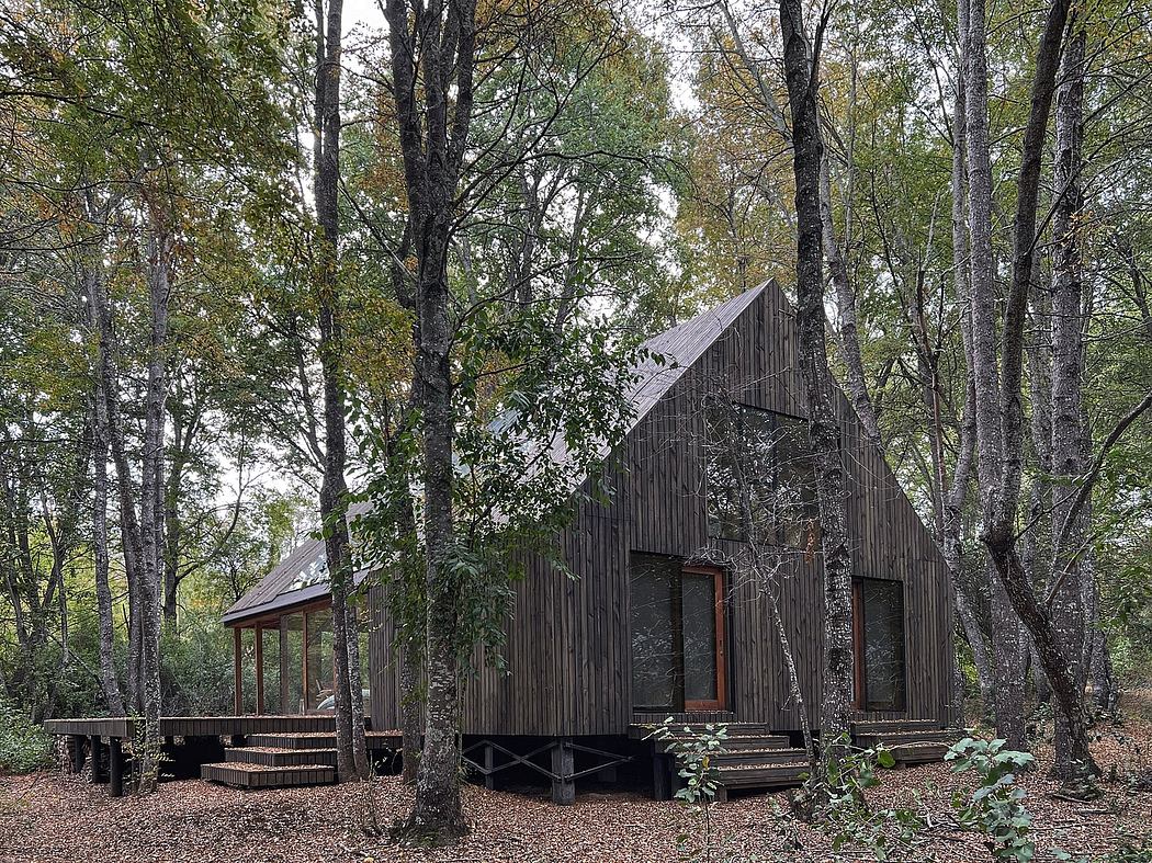 A rustic cabin nestled in a lush, forested setting, featuring a peaked roof and wooden siding.