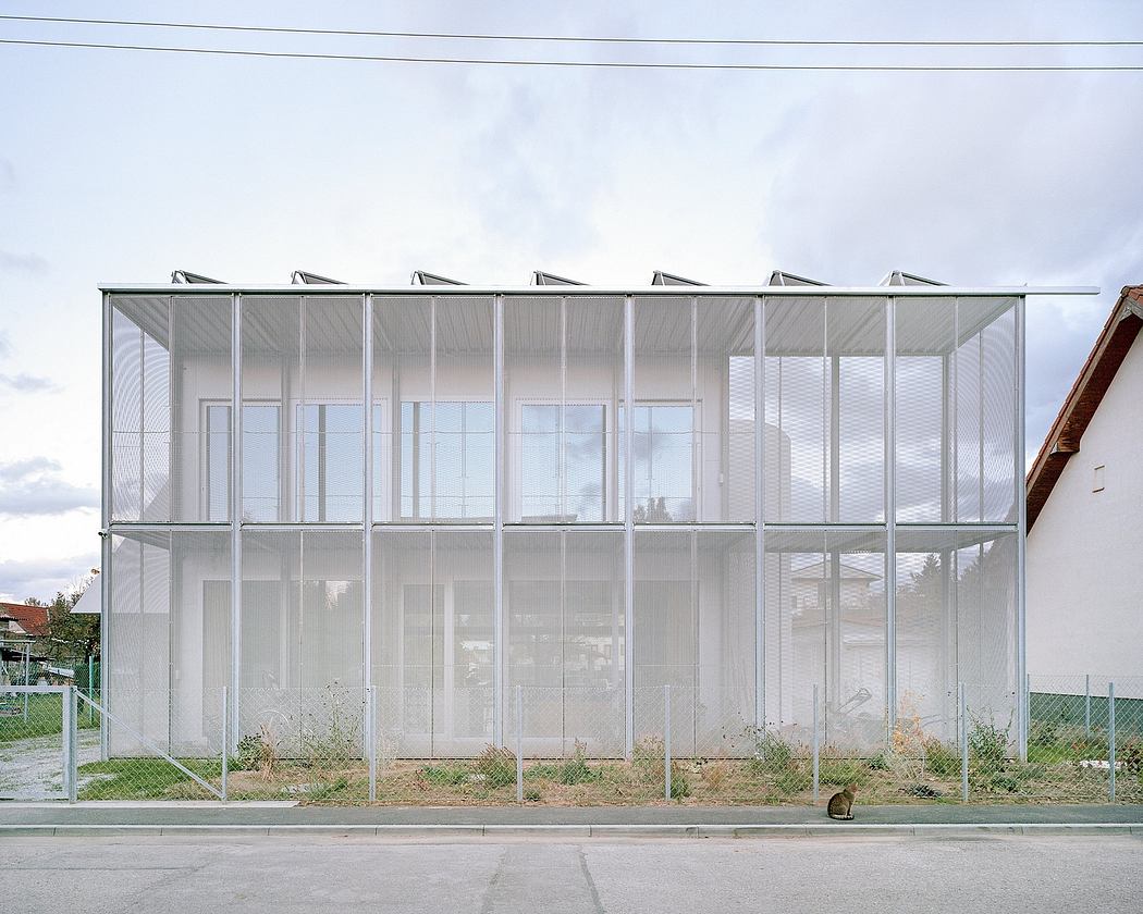 A modern glass and steel structure with a geometric design and expansive windows.