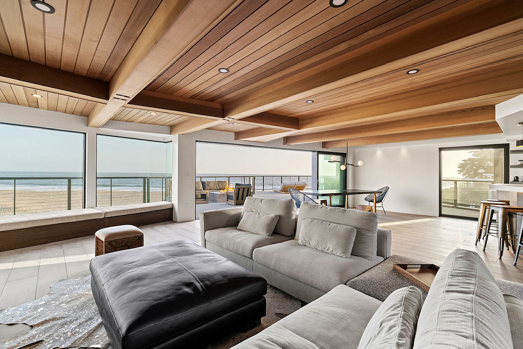 Spacious room with wooden beamed ceiling, large windows overlooking the beach.