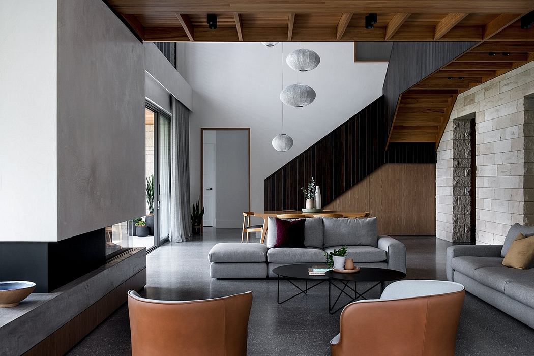 Modern, open-plan living space with wooden ceiling beams, stone walls, and minimalist furniture.