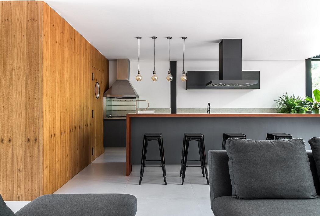 Modern kitchen with sleek black cabinetry, wooden accent walls, and pendant lighting.