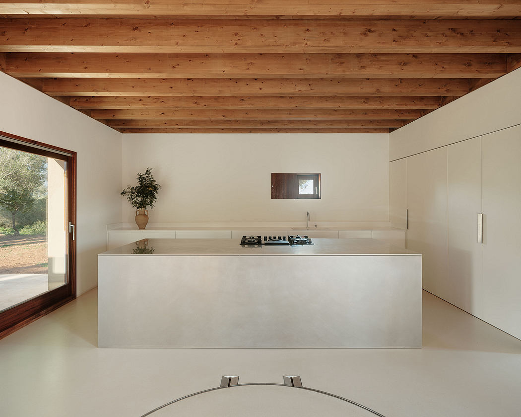Spacious kitchen with exposed wooden beams, modern concrete counter, and large windows.