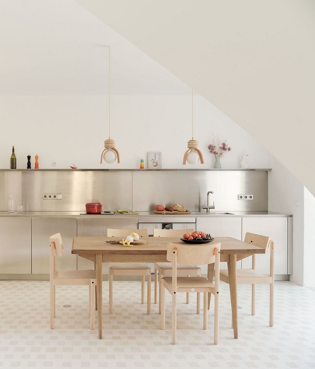 Minimalist kitchen design with wooden dining table and chairs, pendant lighting.