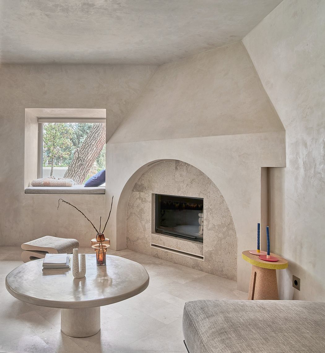 Minimalist living space with arched fireplace, window nook, and modern furnishings.