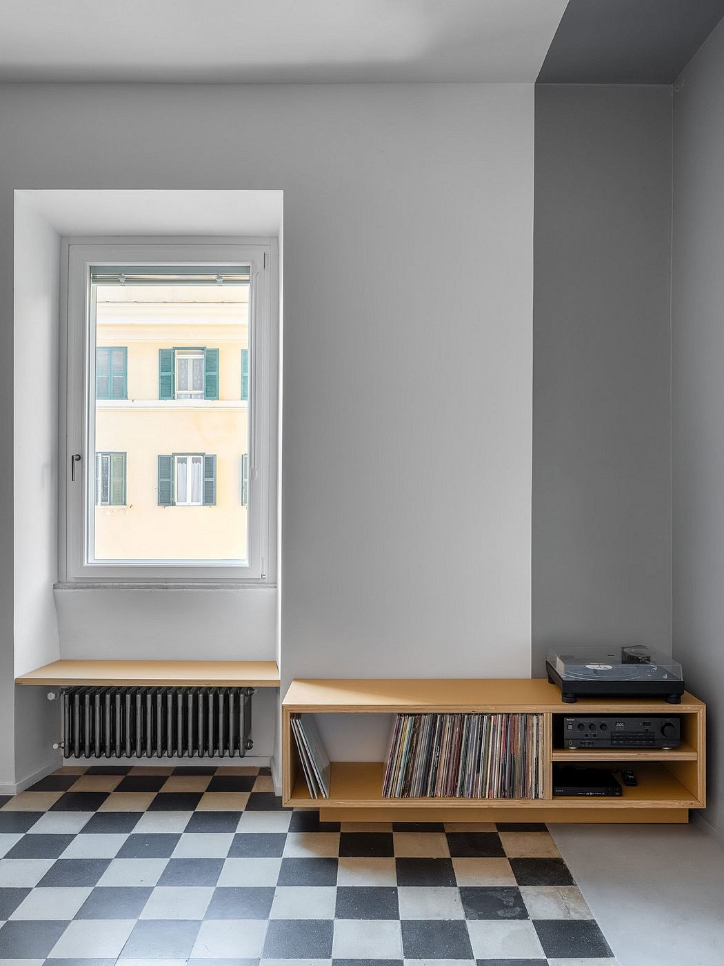Minimalist room with checkered floor, wooden media cabinet, and large window framing exterior.